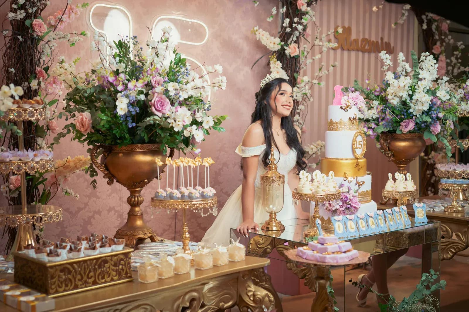 Birthday dessert table with florals, a tiered cake and the guest of honour