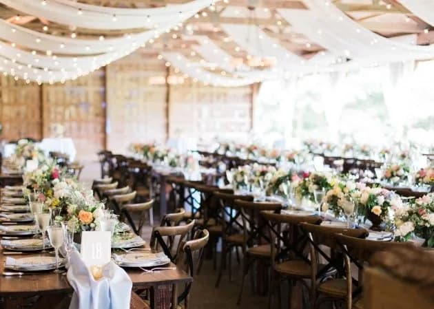 Long wooden dining tables with florals beneath fairy lights and draped fabric at The Landmark