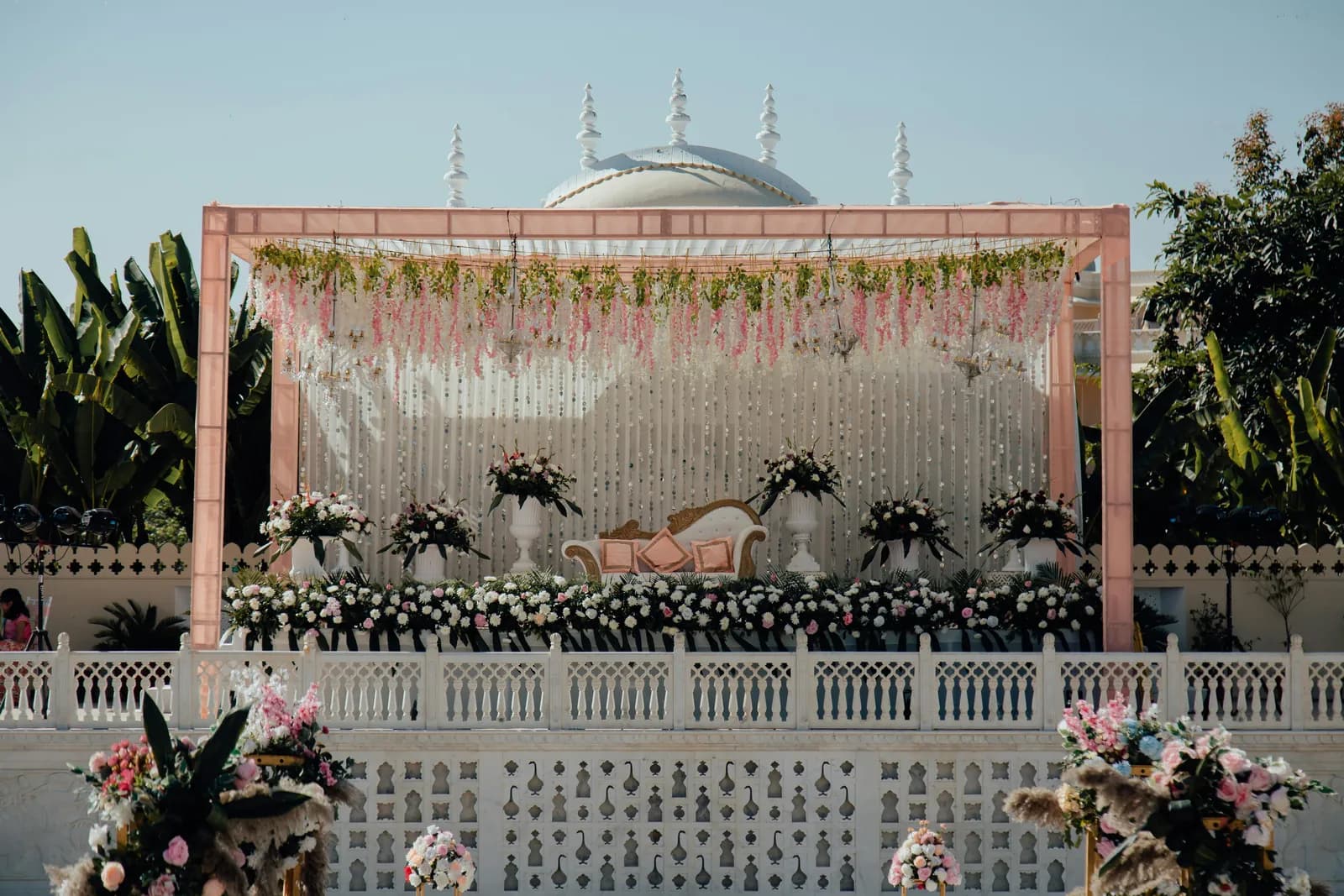 Flower-draped mandap stage with a white sofa on an open-air terrace