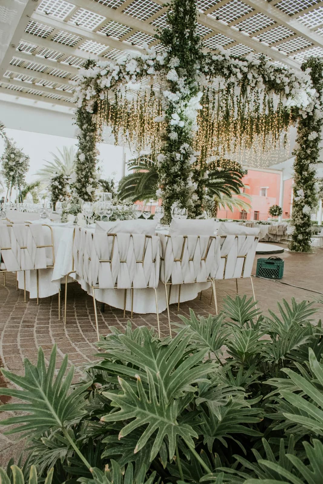 Glass-roofed conservatory with hanging greenery over banquet tables