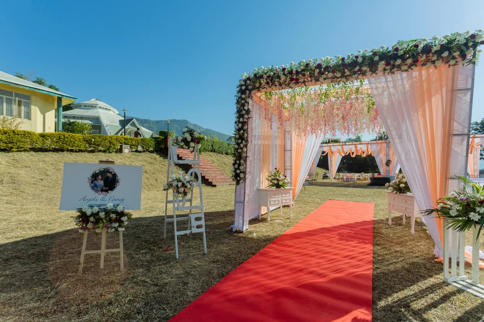 Floral entrance arch and red carpet leading onto a hillside lawn