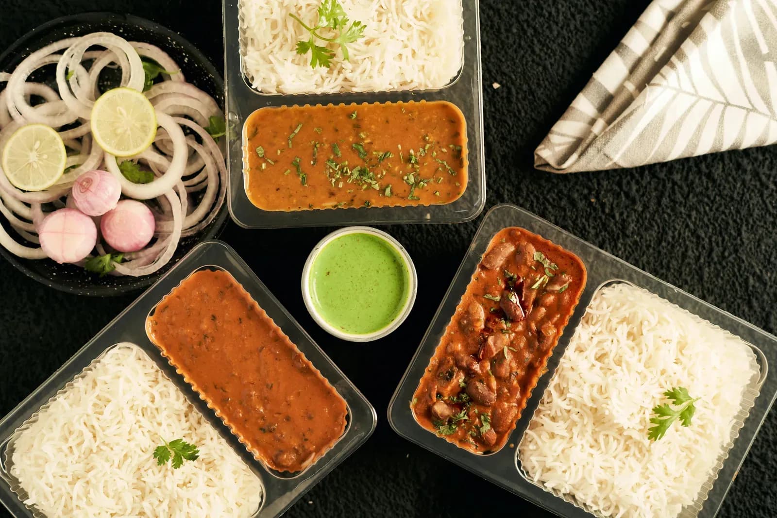 Packed meal boxes with rice, dal, curries, green chutney and sliced onion
