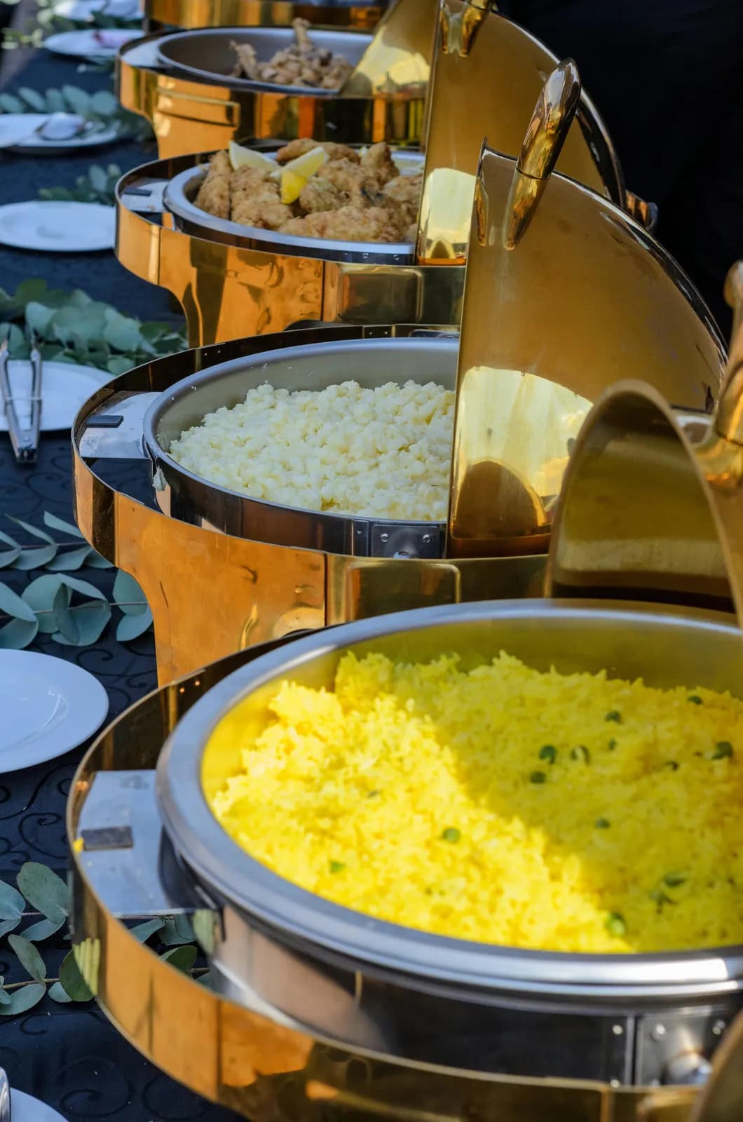 Row of chafing dishes with saffron rice and curries on a wedding buffet
