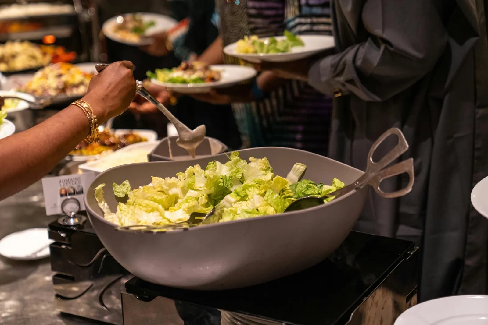 Guests helping themselves to salad and dishes at a buffet counter