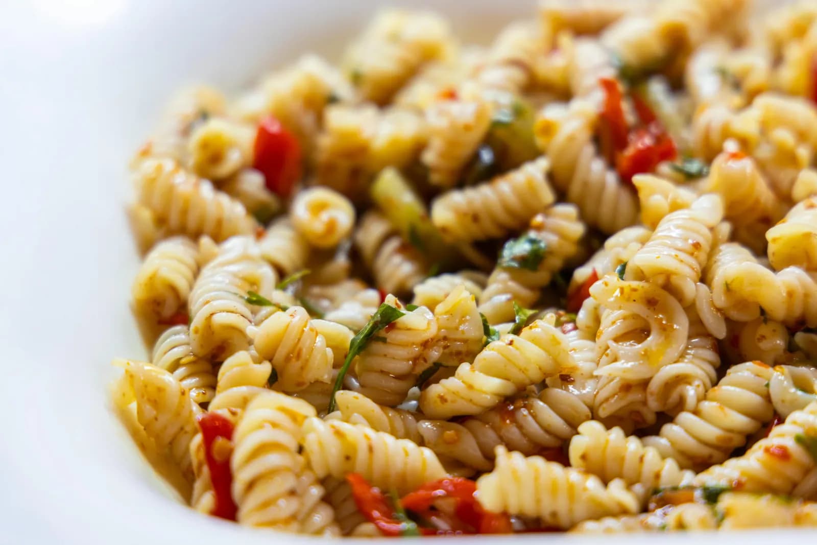 Close-up of fusilli pasta tossed with peppers and herbs