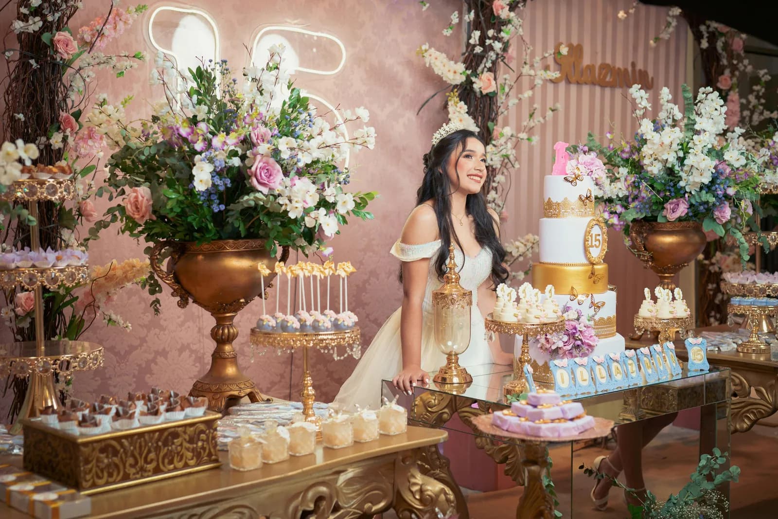 Birthday dessert table with florals, a tiered cake and the guest of honour