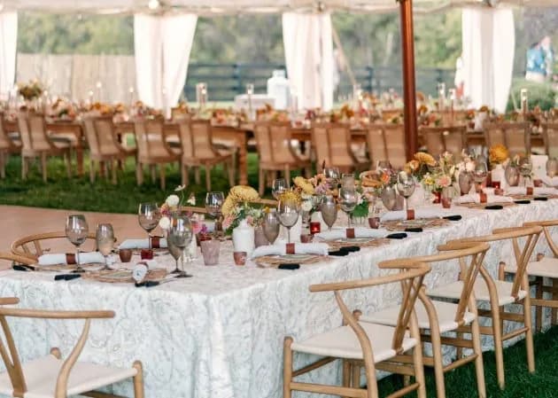 Long tables with florals and glassware under a garden marquee at Duportail House