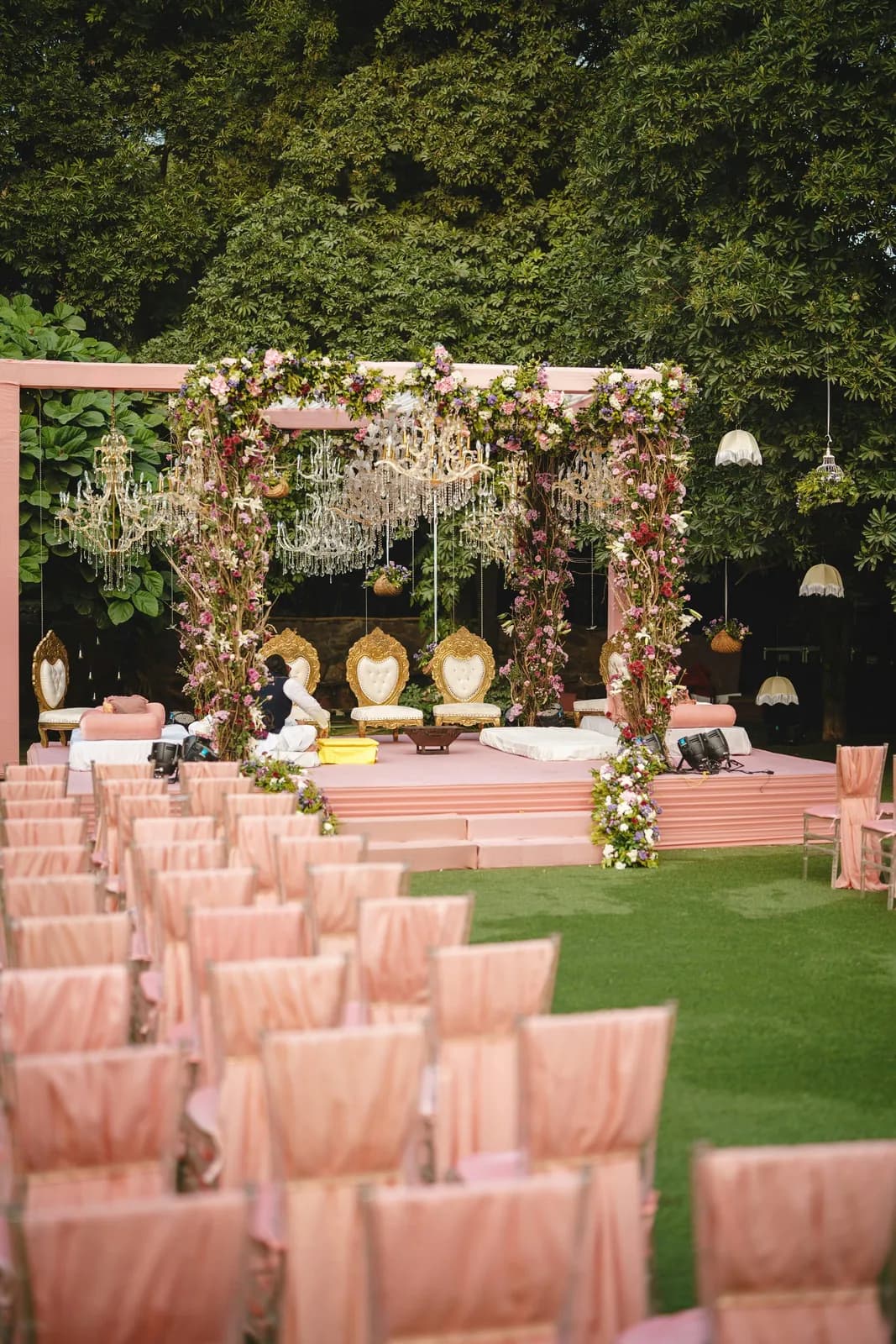 Garden mandap with rows of pink-draped chairs on the lawn